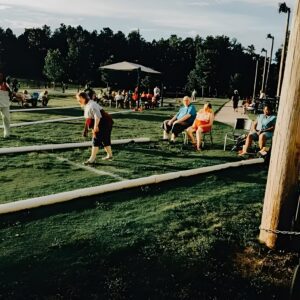 People playing and watching outdoor bocce game.