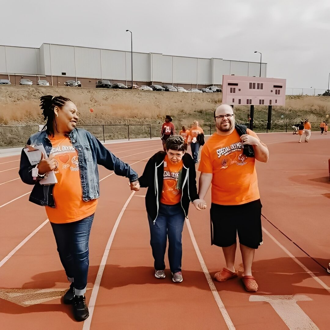 People walking on a track, wearing orange.